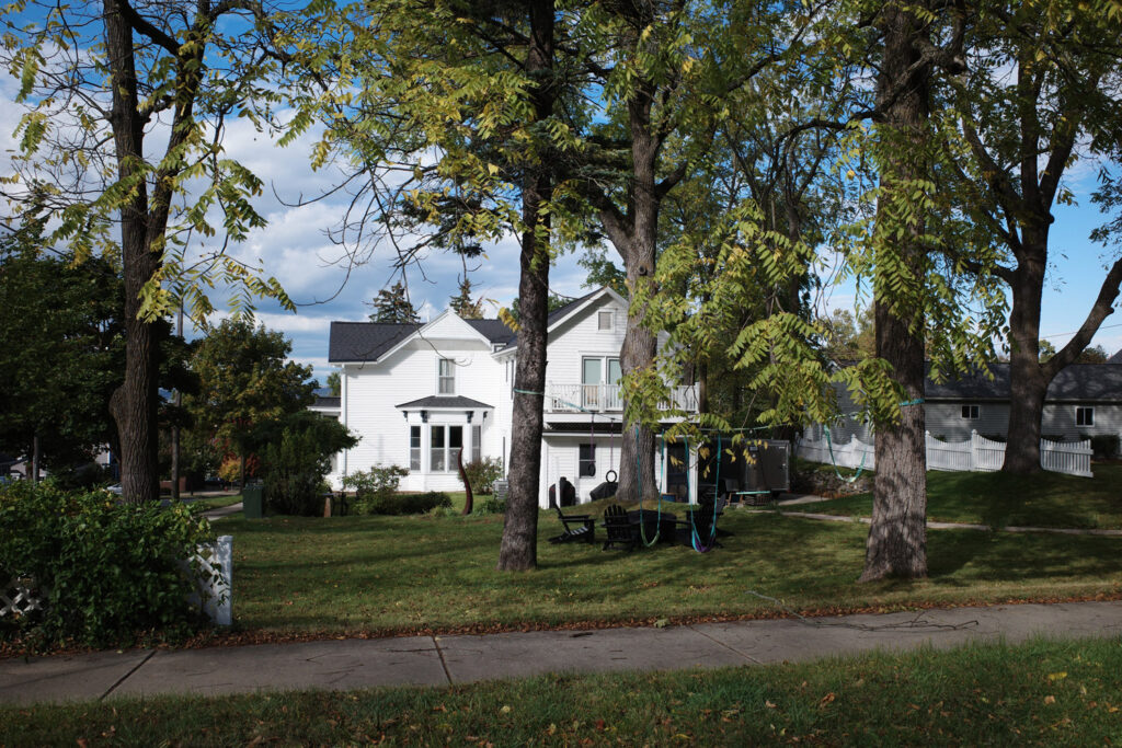 White house with rope swings in yard.