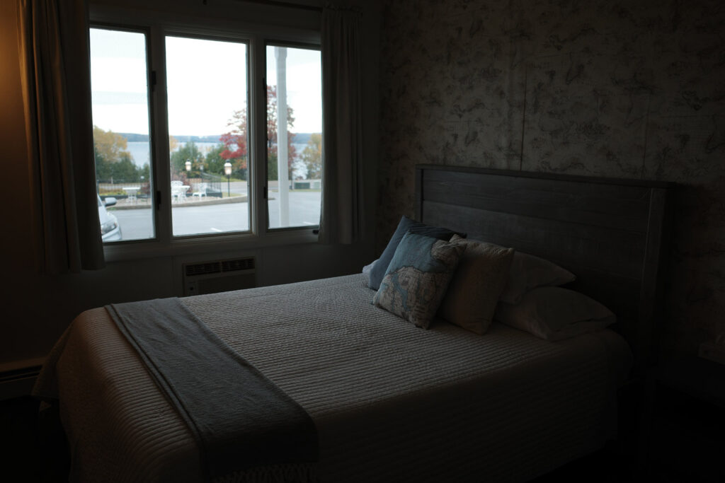 Bed looking out window in motel room.