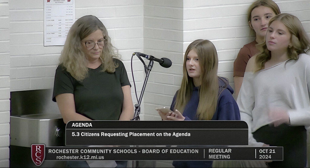 Screenshot of Liliana speaking at schoolboard meeting video with text reading "AGENDA 5.3 Citizens Requesting Placement on the Agenda ROCHESTER COMMUNITY SCHOOLS - BOARD OF EDUCATION rochester.k12.milus REGULAR MEETING OCT 21 2024"