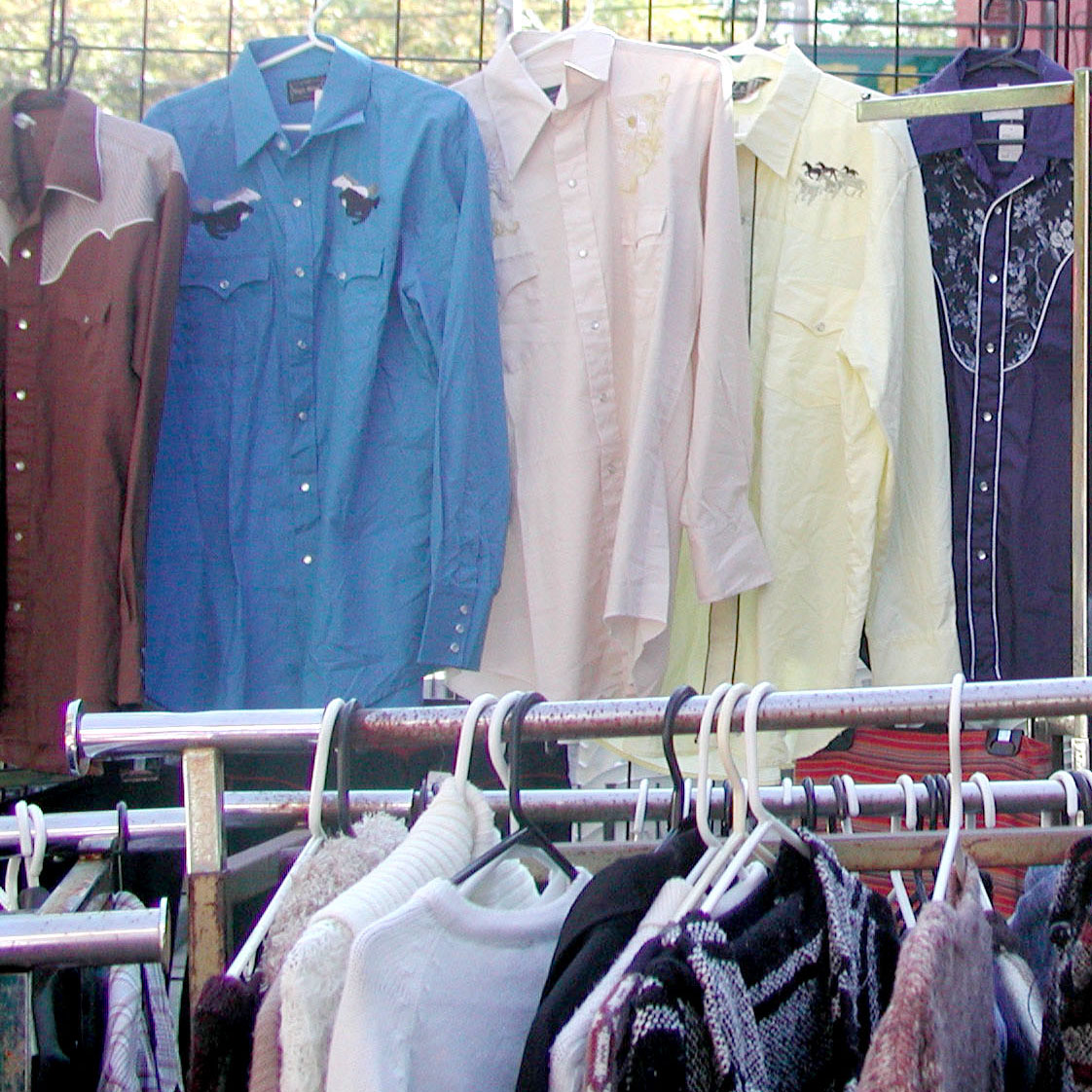 Clothes on rack at thrift shop.