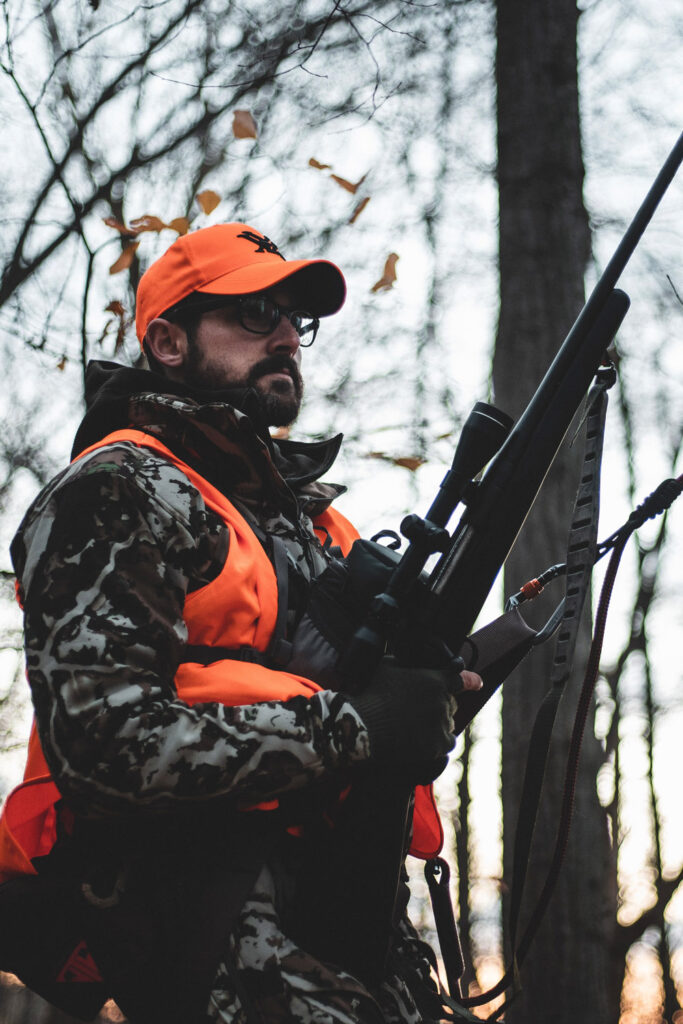 Man with rifle in camo and orange hunting garb