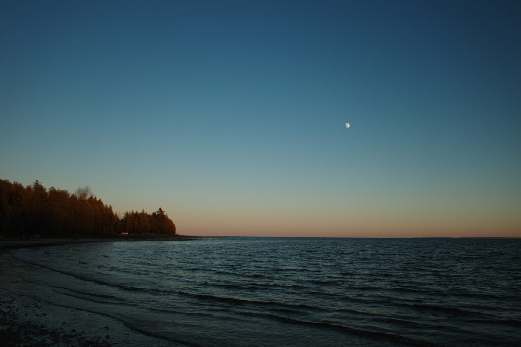 View of beach and moon in sunset sky