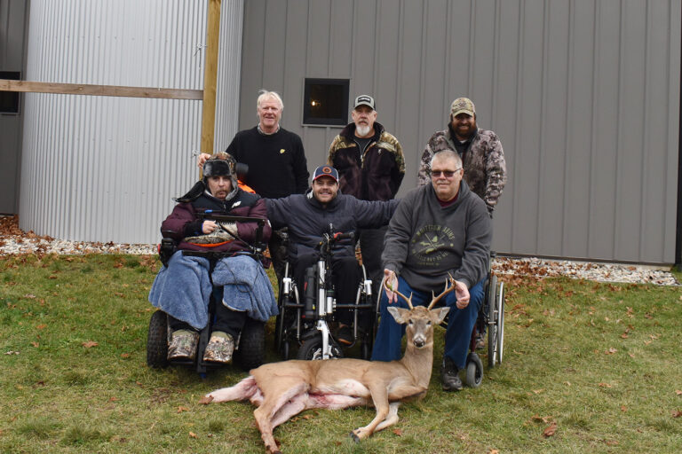 Group of people in wheelchairs posing with dead buck