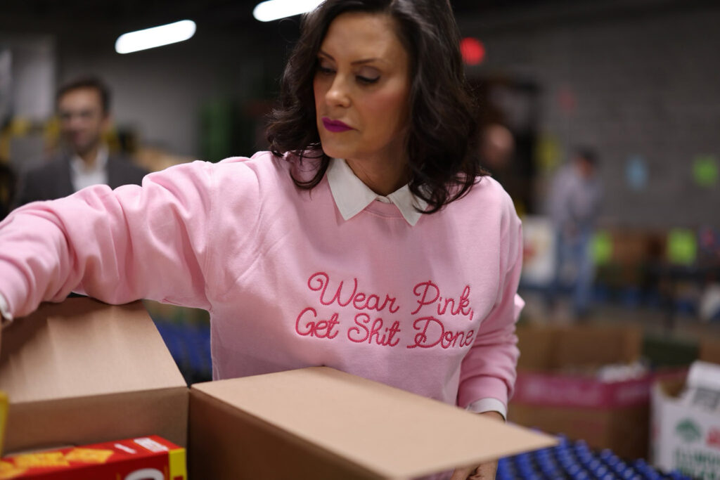 Gretchen Whitmer wearing pink sweater saying "wear pink get shit done"