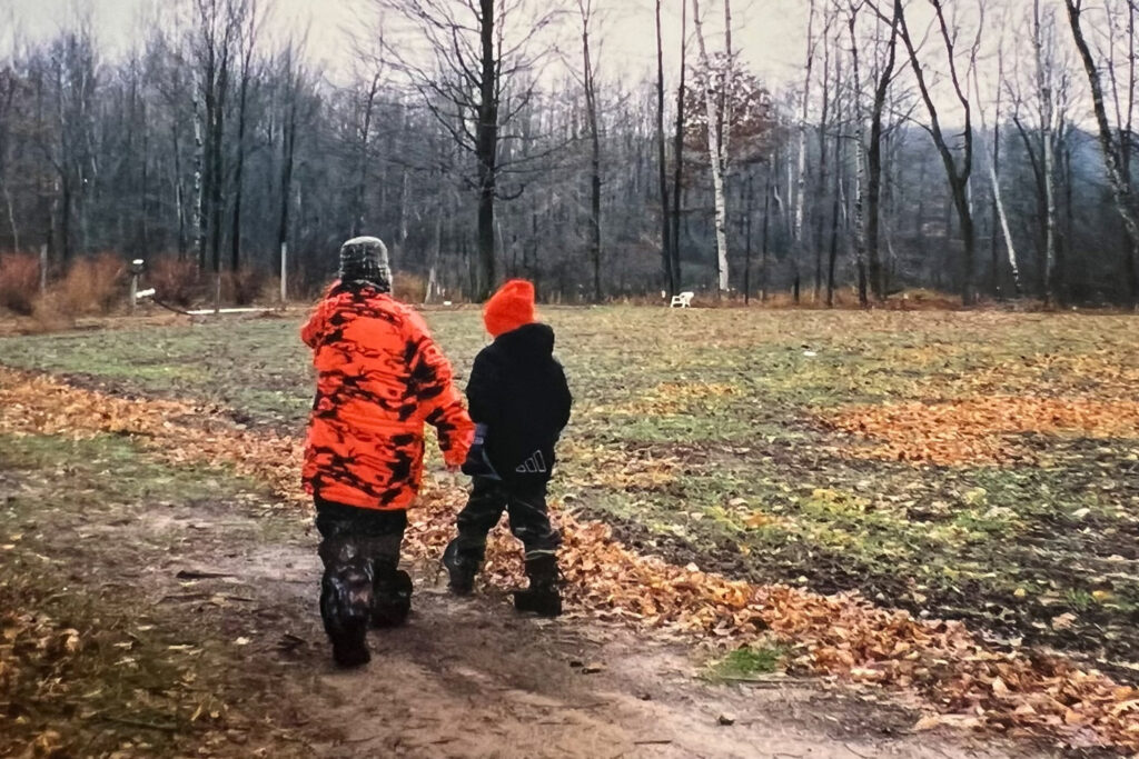 Two boys in hunting gear walking down trail