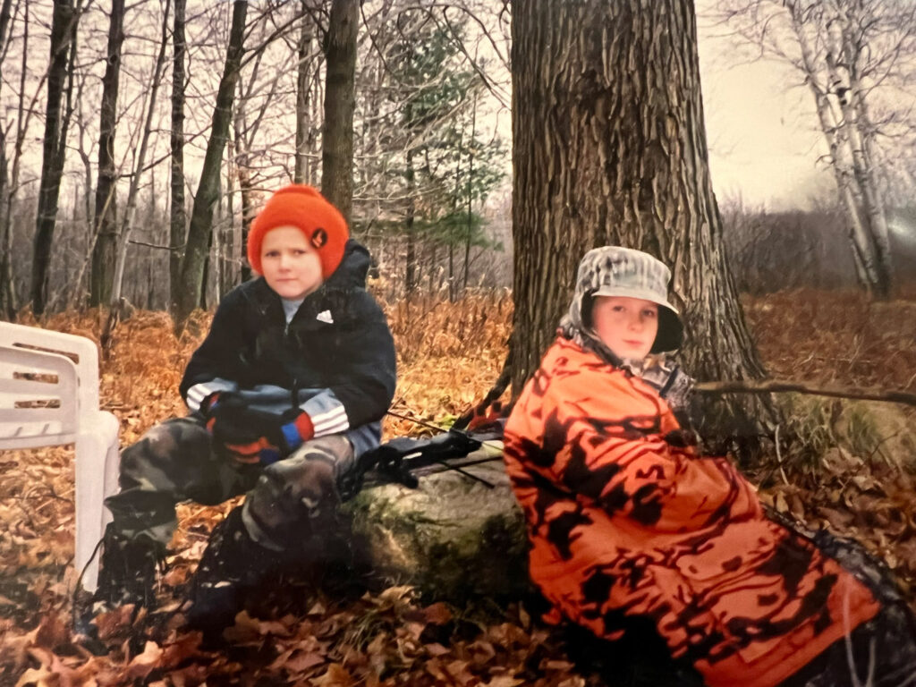 Two boys in hunting gear in the woods