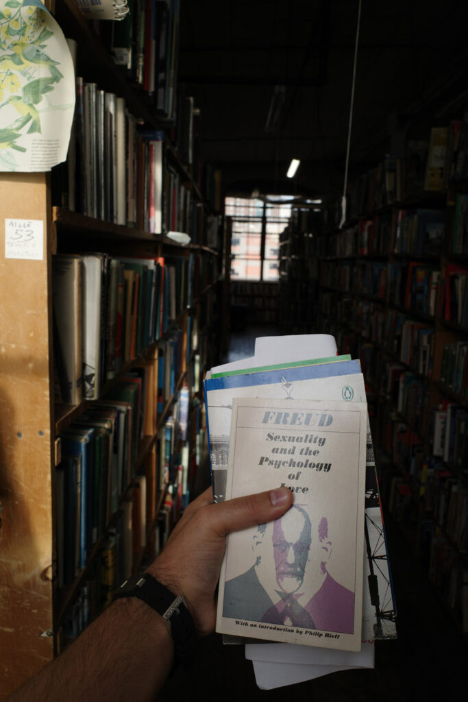 Dark bookshelves and man's hand with Freud's "Sexuality and the Psychology of Love" in hand