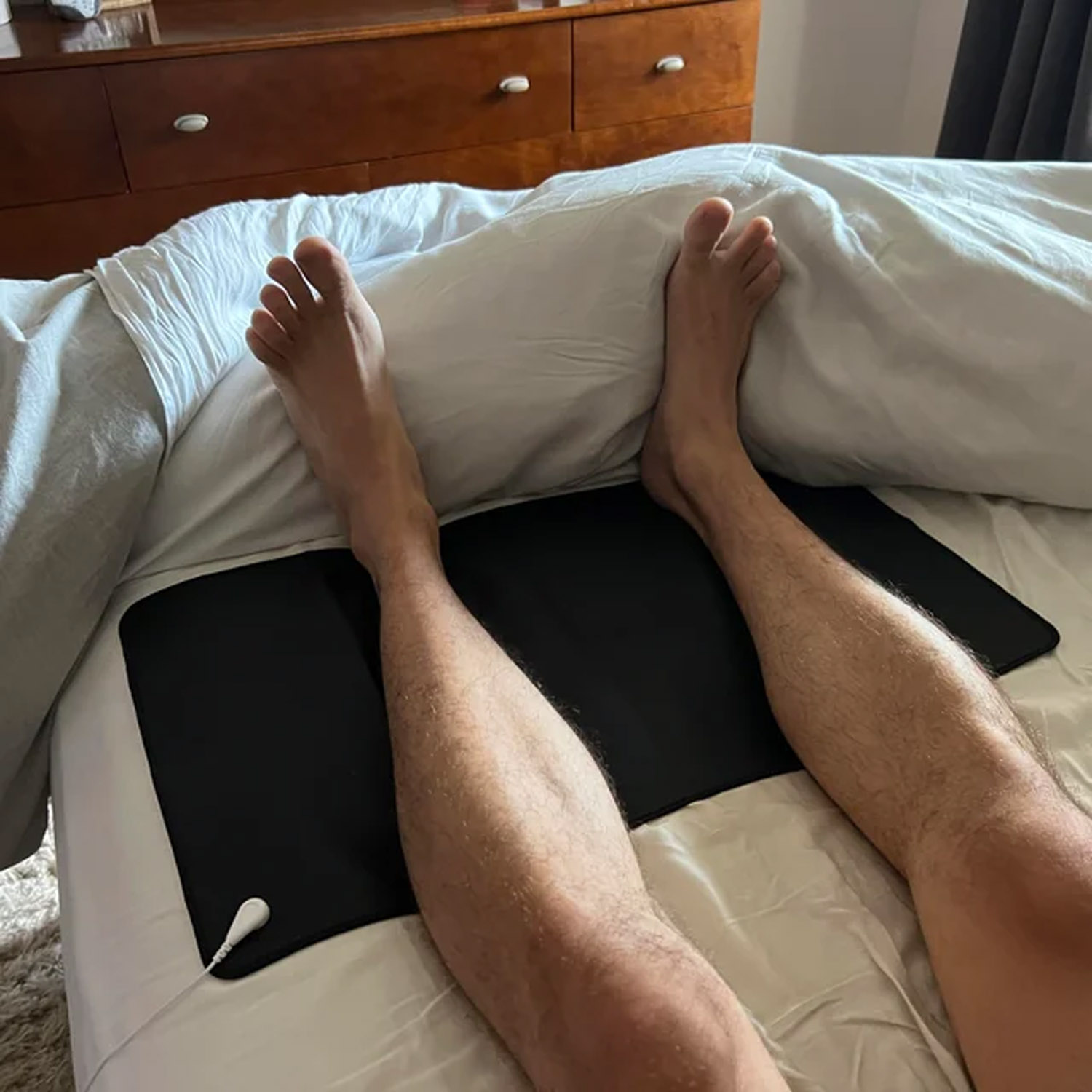 grounding mat with man's feet on it on bed