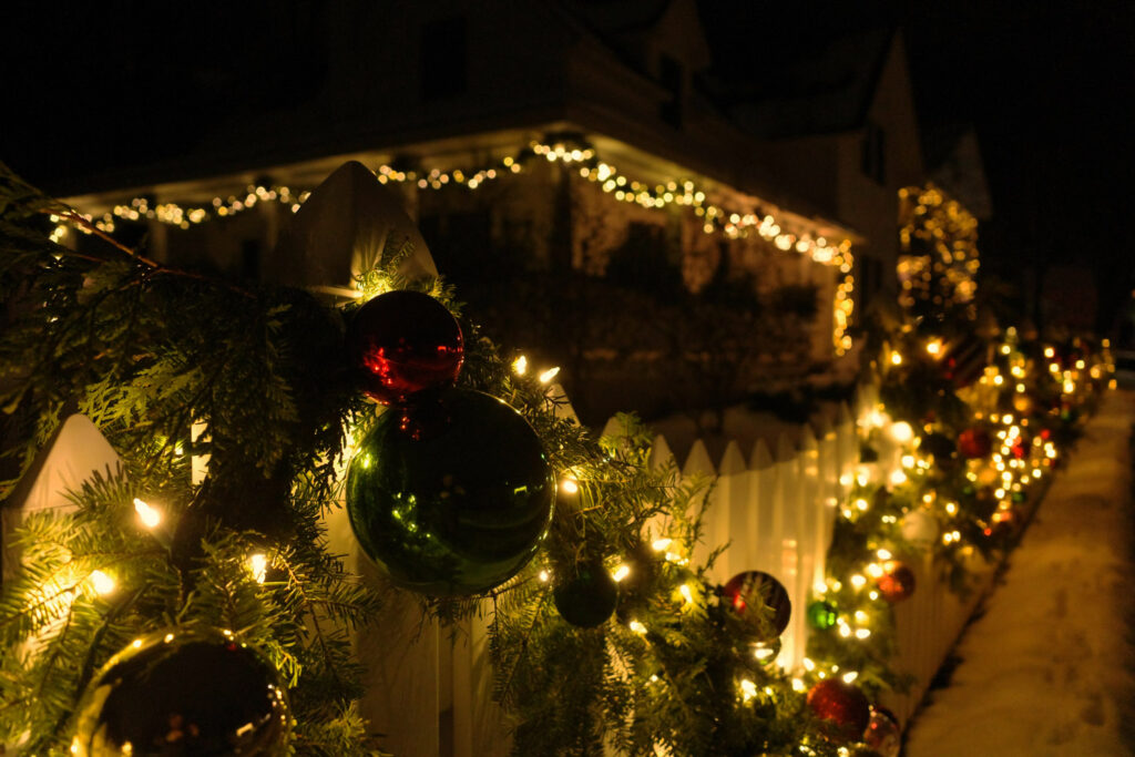 Garland, lights and ornaments hanging on fence at night