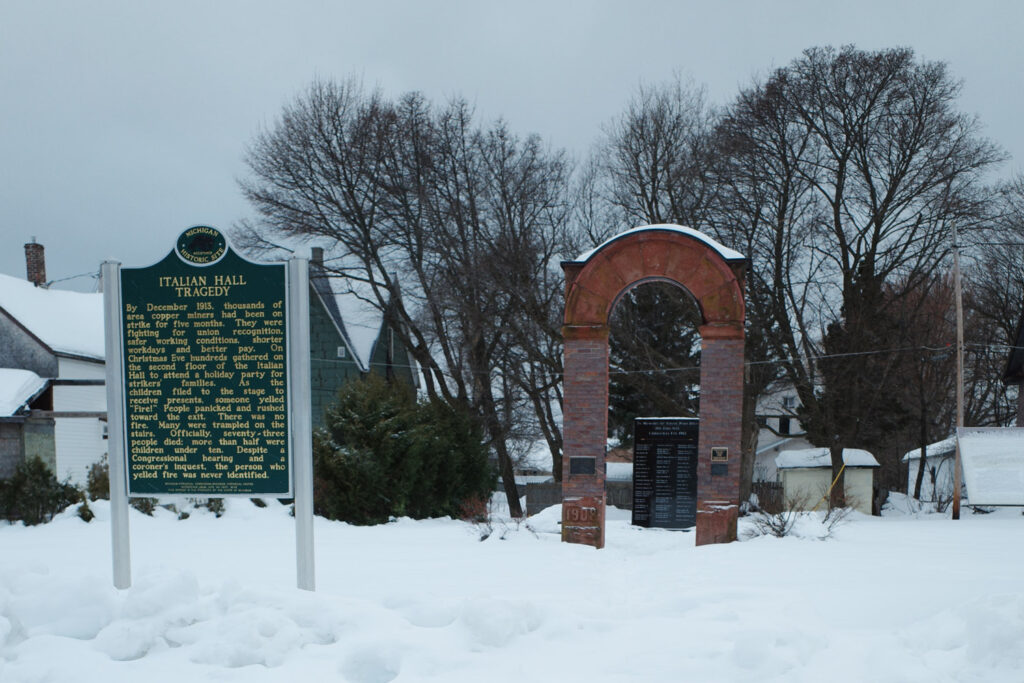 Snow piled in front of sign and commemorative arch