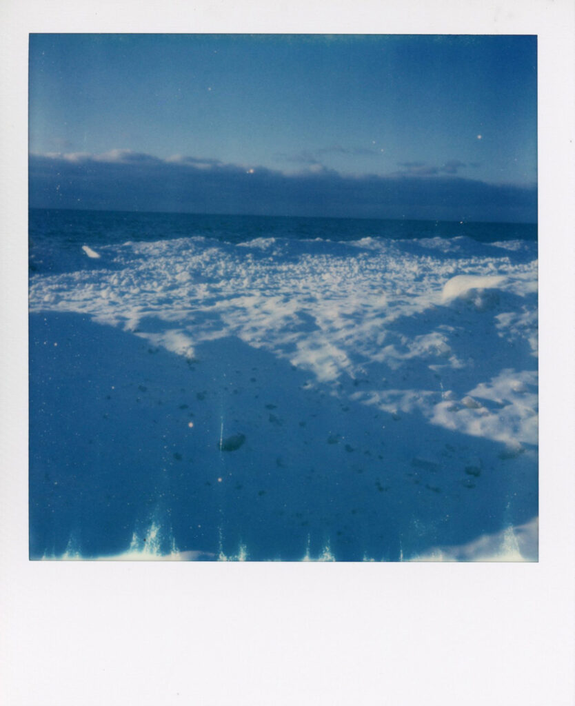 Snow on beach polaroid scan showing ice cracks with blue hue