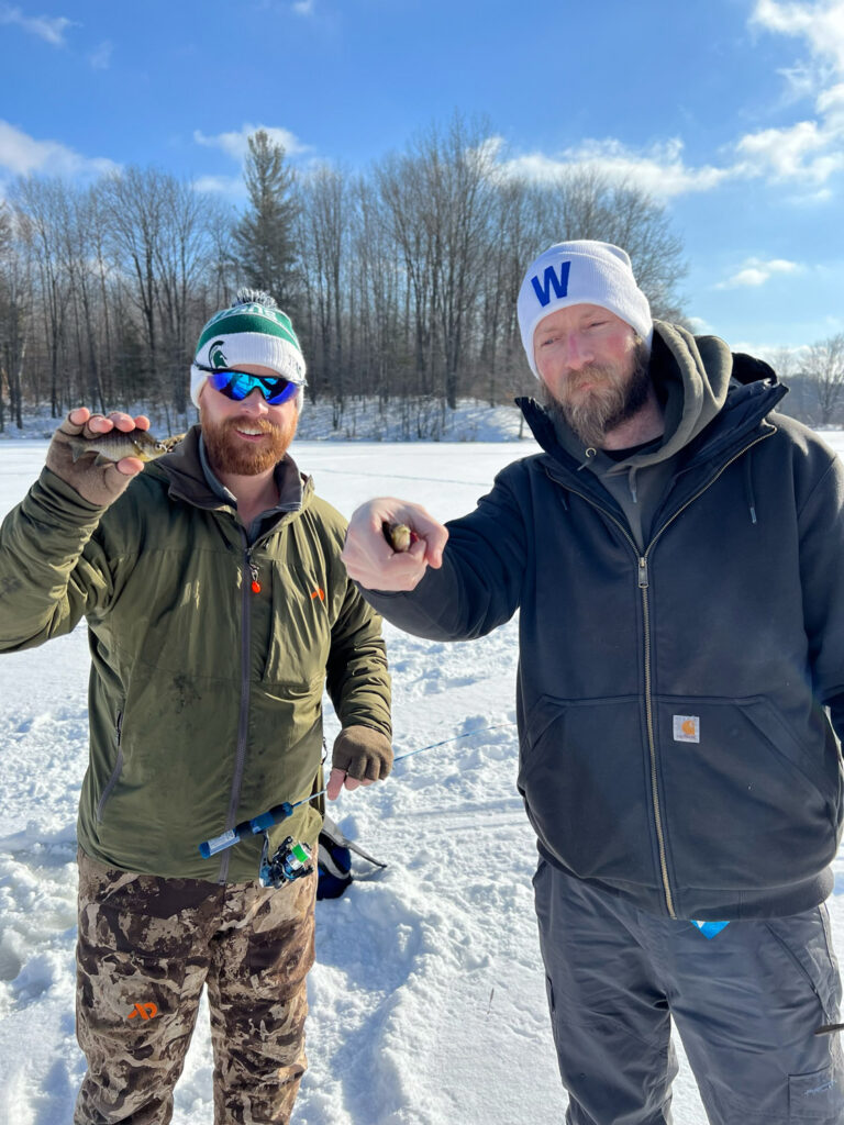 Two men holding small fish