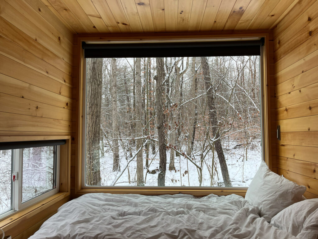 Bed inside small cabin with winter view out window