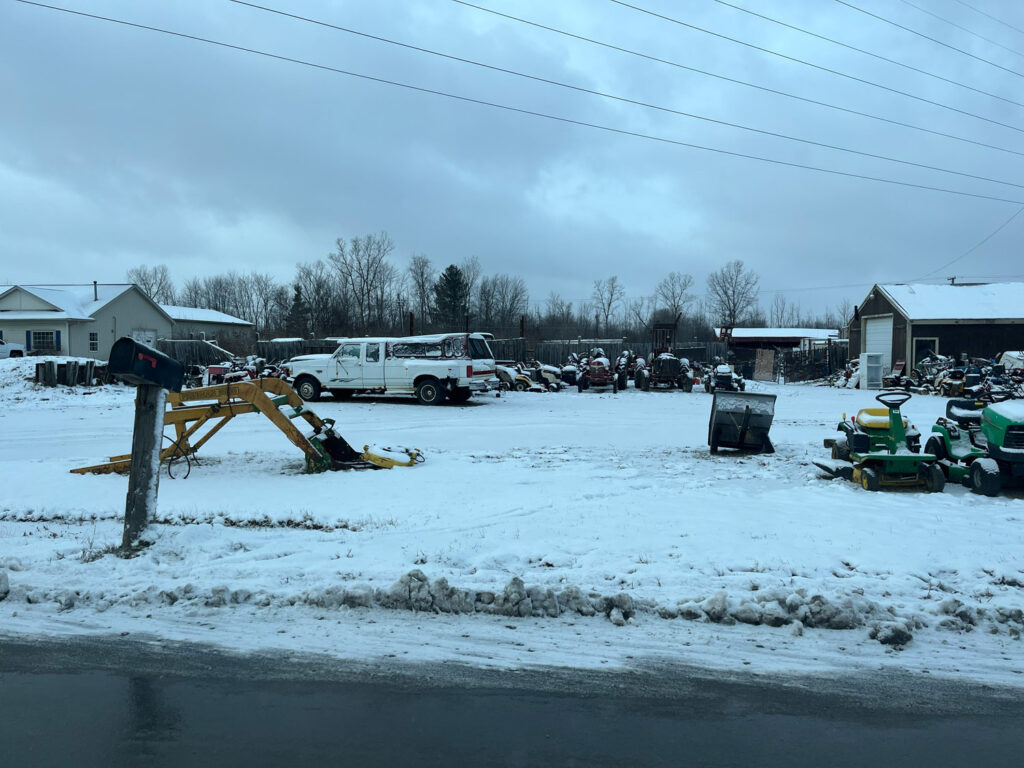 Trucks and lawn mowers covered in snowy lot