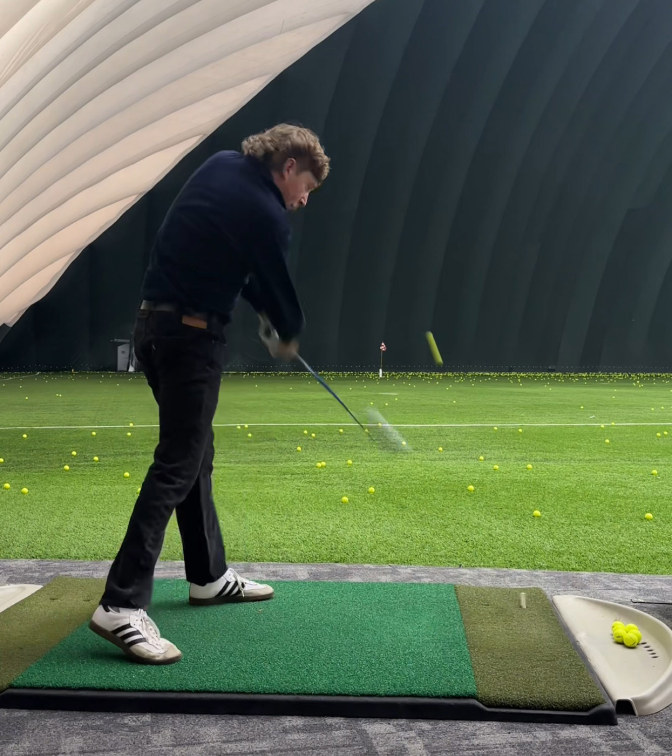 man hitting ball in golf dome