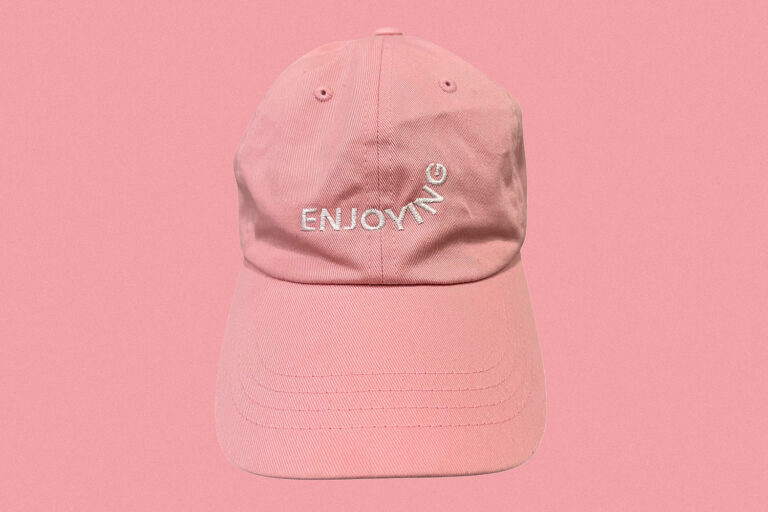 pink hat saying Enjoying on pink background