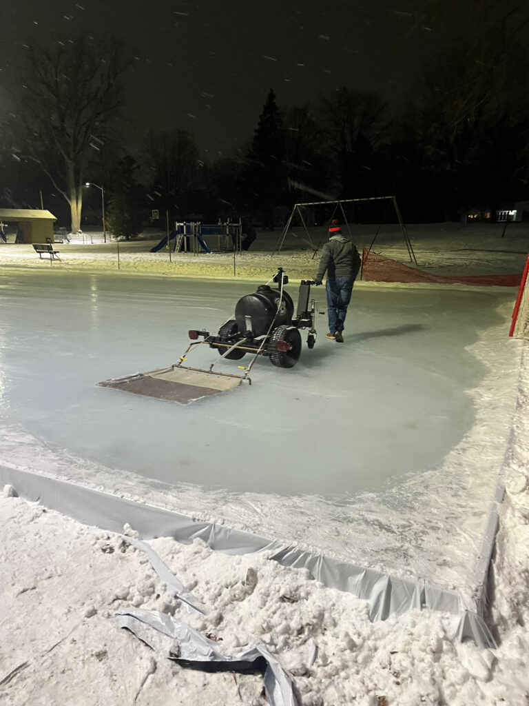 man smoothing outdoor hockey rink