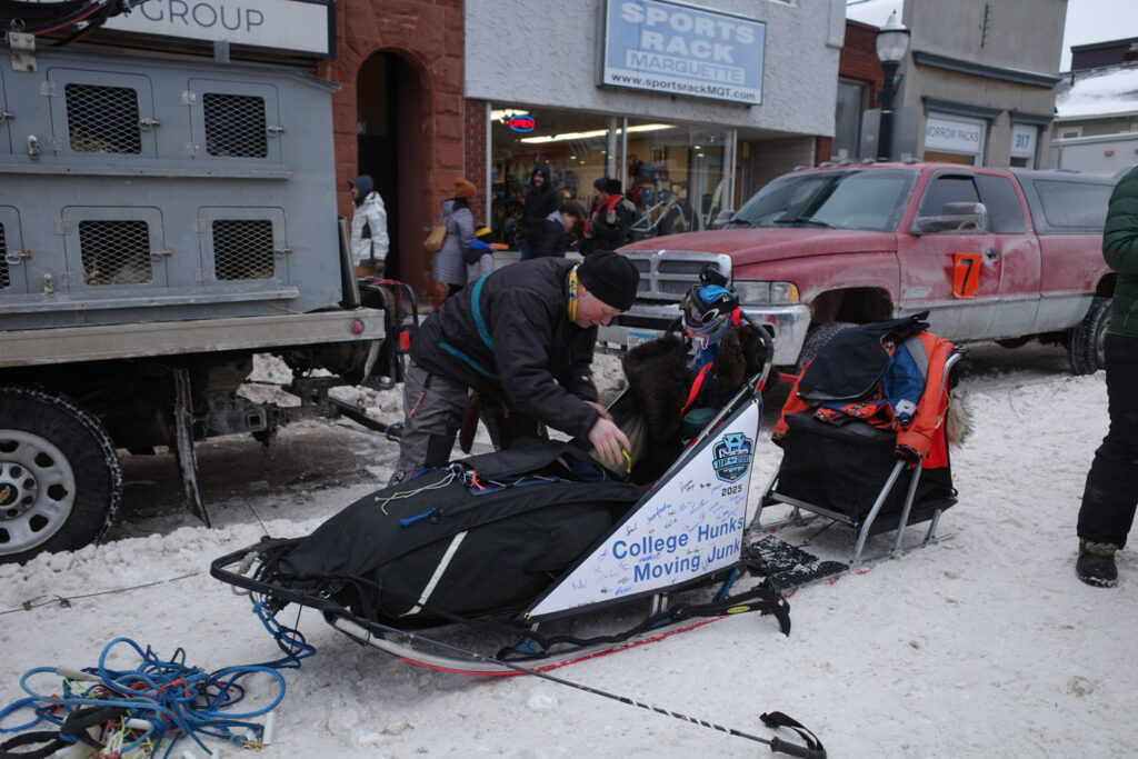 "College Hunks Moving Junk" dog sled team preparing sled for race