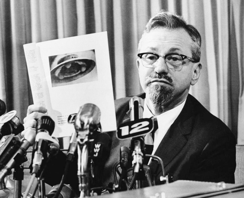 man explaining swamp gas theory at press conference