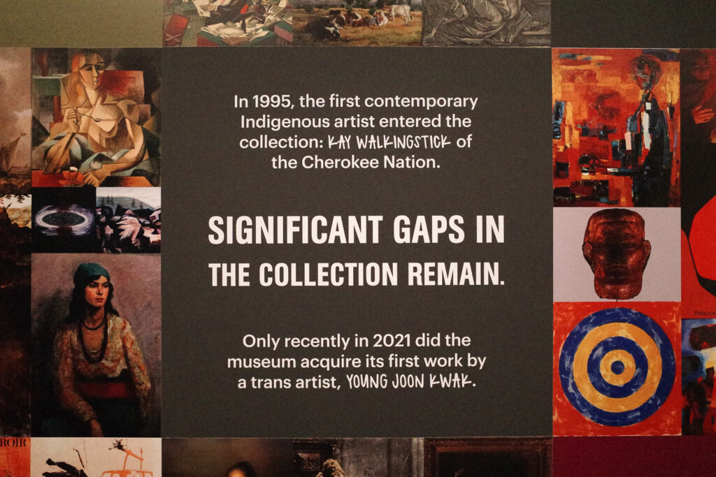 wall text reading "In 1995, the first contemporary Indigenous artist entered the collection: KAY WALKINGSTICK of the Cherokee Nation.
SIGNIFICANT GAPS IN THE COLLECTION REMAIN.
Only recently in 2021 did the museum acquire its first work by a trans artist, YOUNG JOON KWAK."