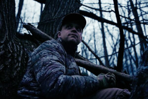 man in dawn woods in camo
