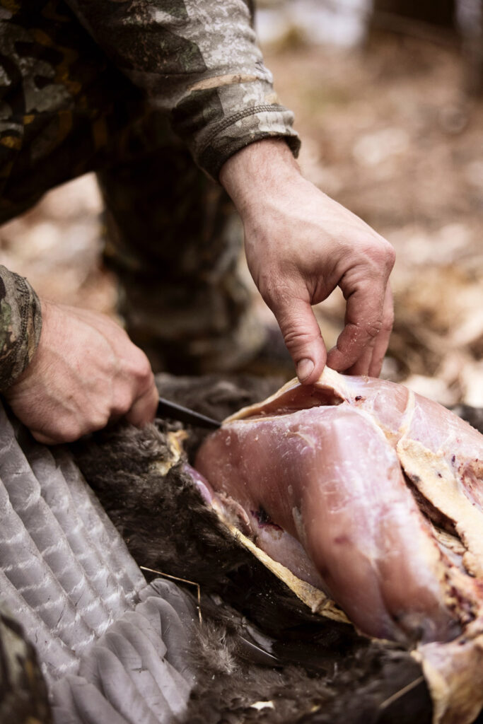 man cutting meat in forest