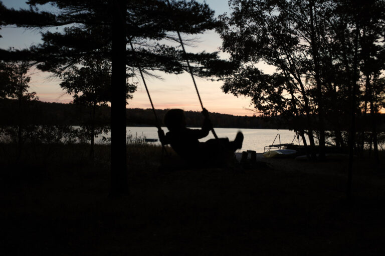 kid on backyard swing at sunset