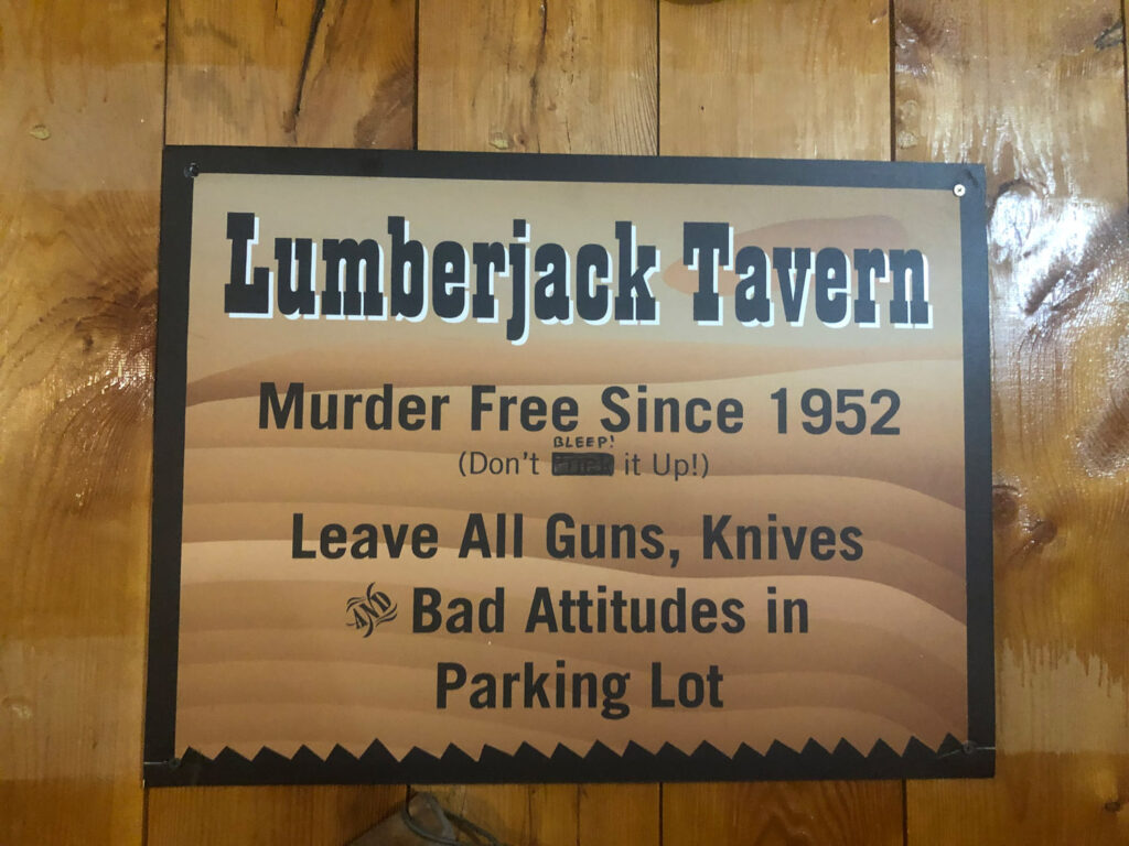 lumberjack tavern sign reading "Lumberjack Tavern
Murder Free Since 1952
BLEEP!
(Don't
it Up!)
Leave All Guns, Knives
Bad Attitudes in Parking Lot"