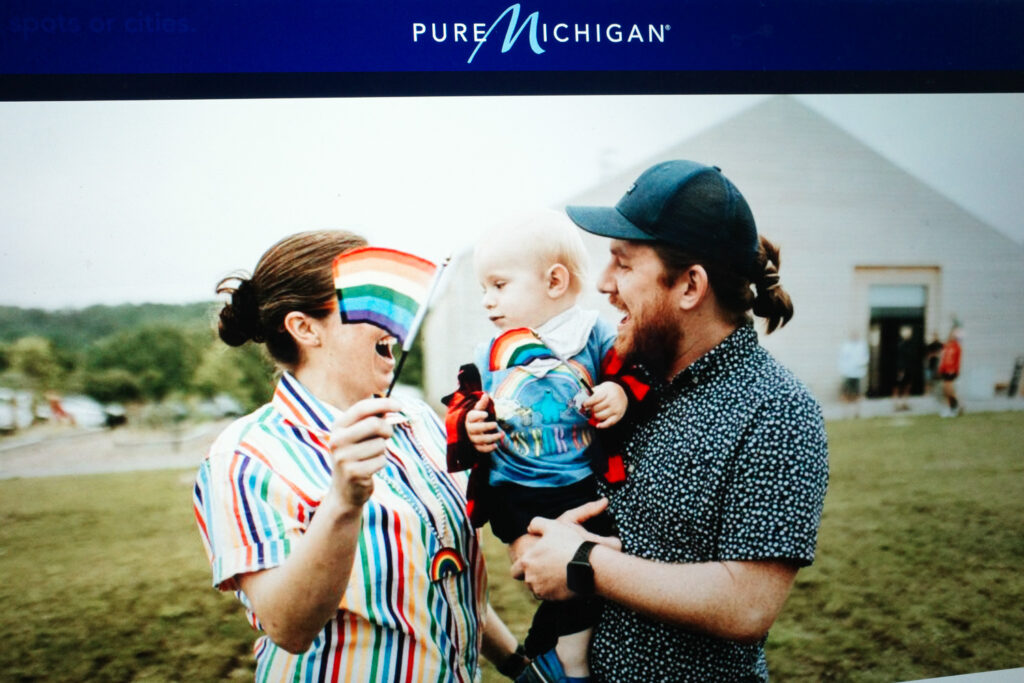 pure michigan site with couple waving rainbow flags with baby