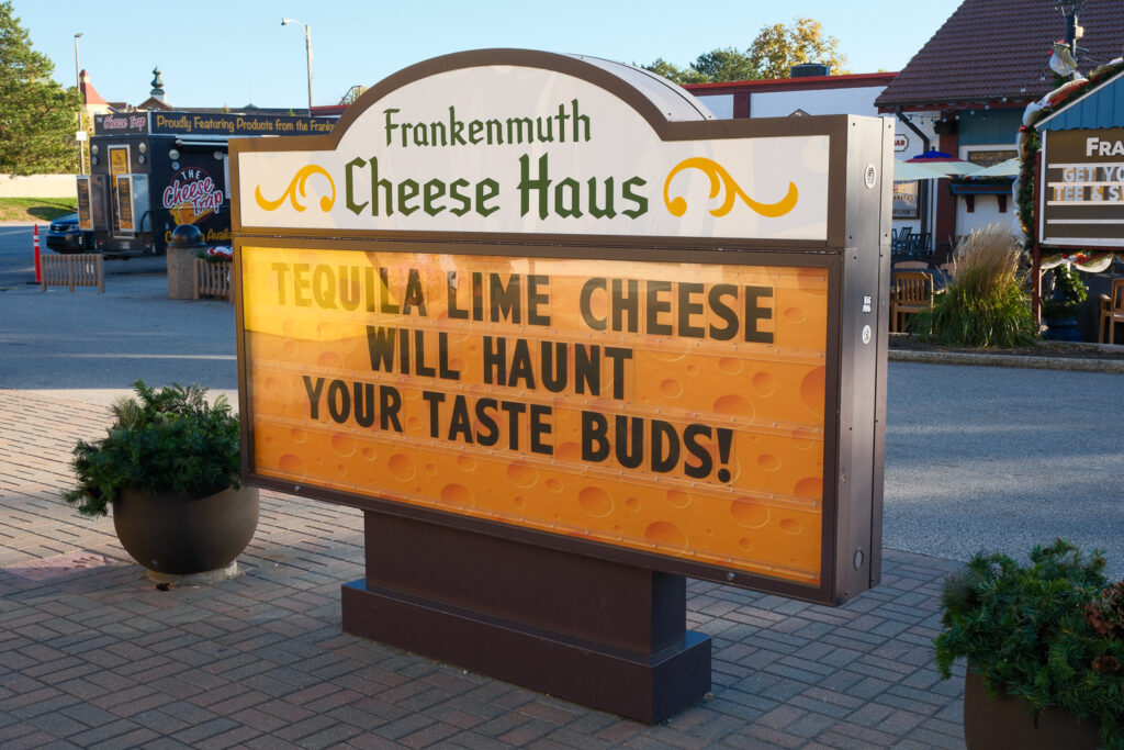 A sign for the Frankenmuth Cheese Haus that says "Tequila lime cheese will haunt your taste buds!" with a graphic of cheese.