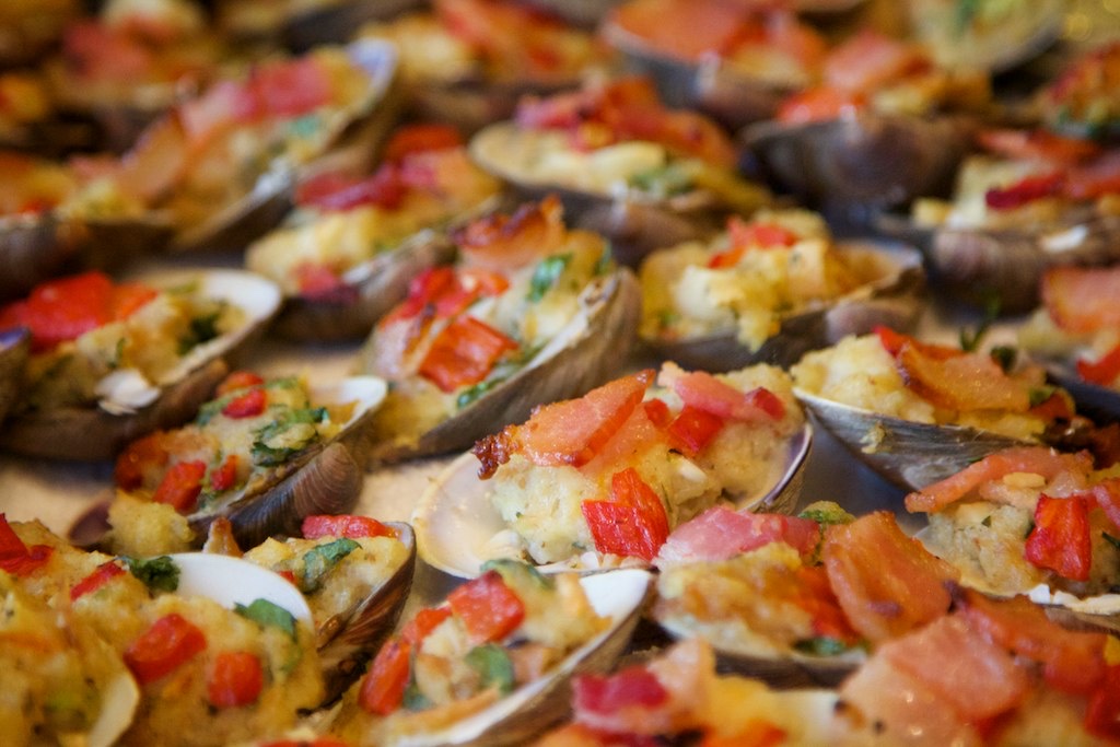 A close-up view of a savory clams casino dish containing pieces of vegetables and other ingredients, creating a colorful and textured appearance.