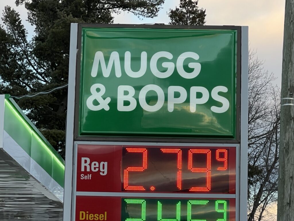 A large green sign displays the text "MUGG & BOPP" with two digital displays showing fuel prices of $2.79 for regular self-serve and $3.11 for diesel.