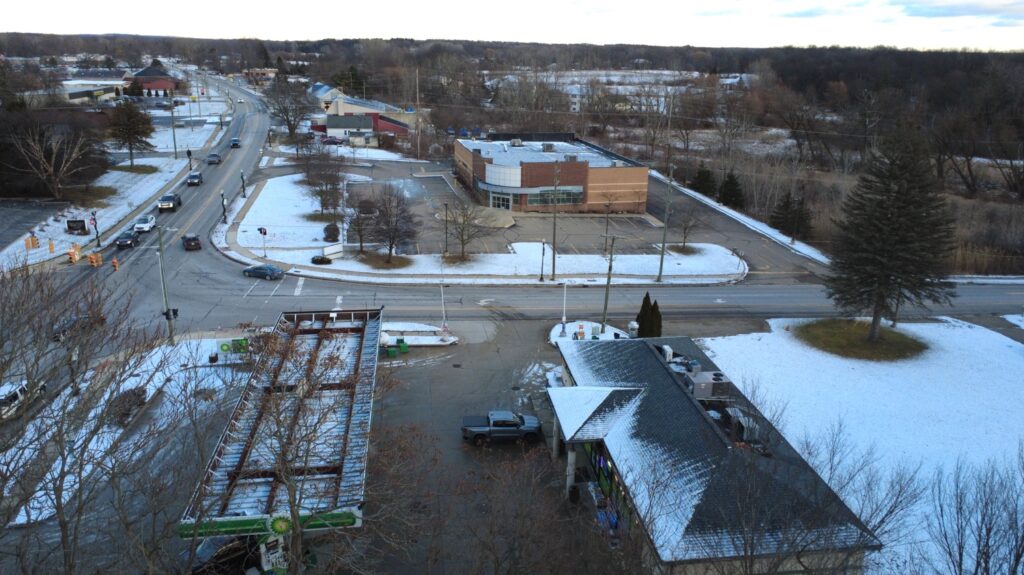 Aerial view of a snowy town with a main road, buildings, and a wintry landscape.