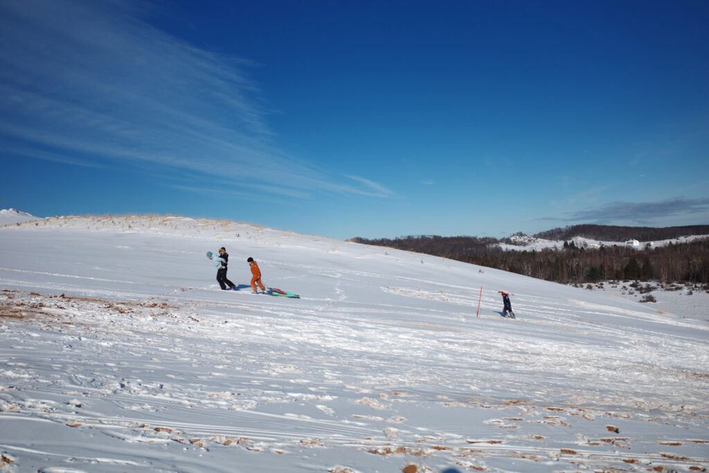 dune climb in winter with sledders